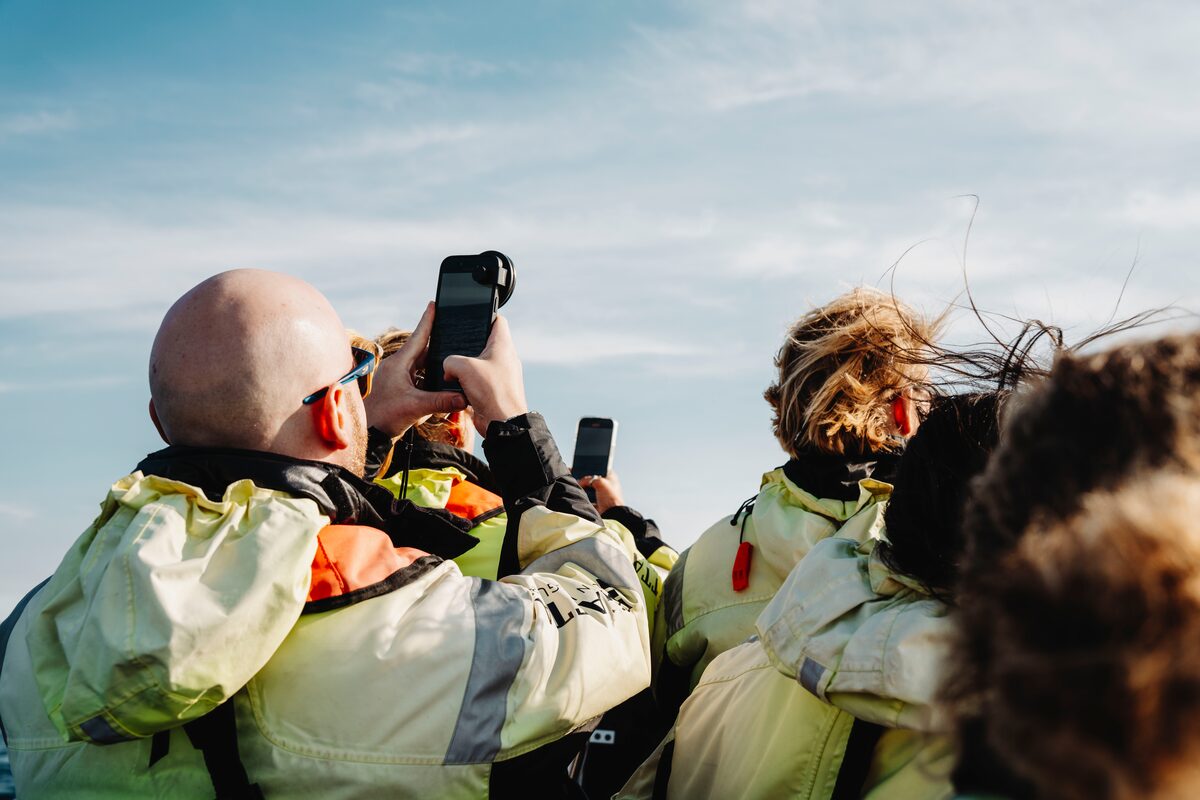 Tourists photographing out at sea on whale watching tour.