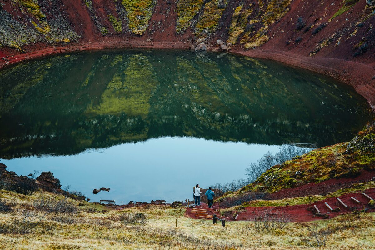 Tourists down inside Kerids crater, viewing the volcanic lake during summer in Iceland,