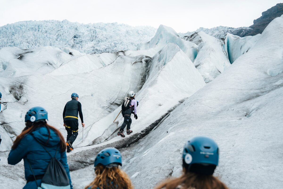 A group of hikers climbing upward on glacier in Skaftafell, navigating through crevasses.