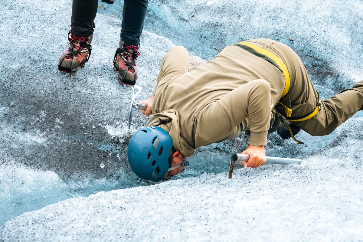 Tourist kneeling down on glacier floor sipping water from a glacial river in Skaftafell.