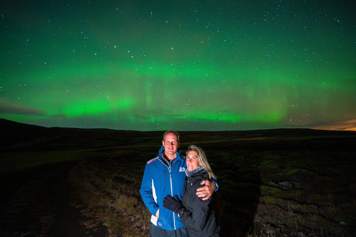 Couple hugging underneath aurora borealis in Iceland in winter.
