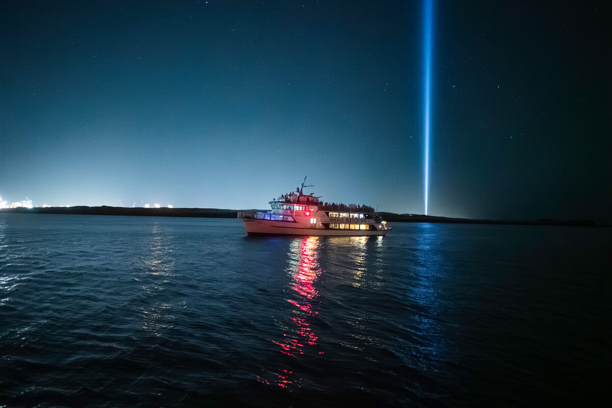 Special tours white boat in ocean at night time hunting for northern lights in Iceland.