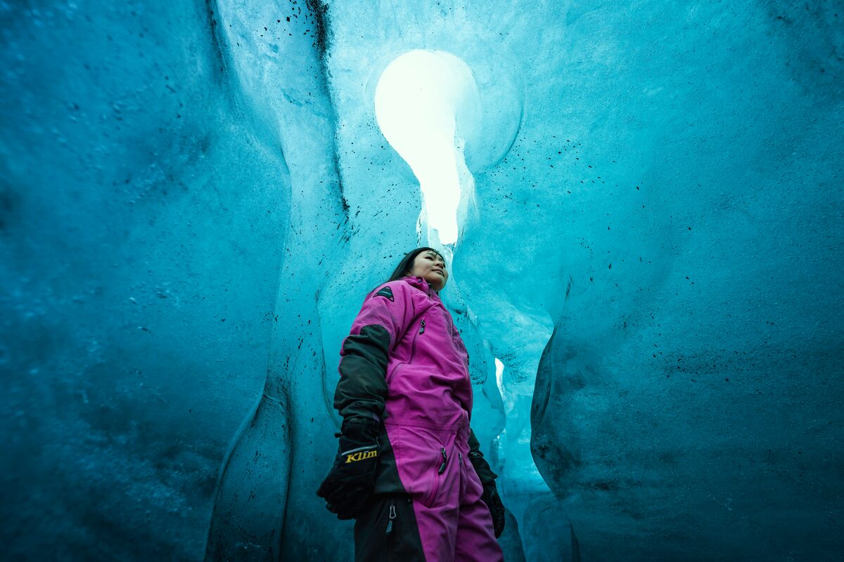 a woman standing under ice ceiling in an ice cave