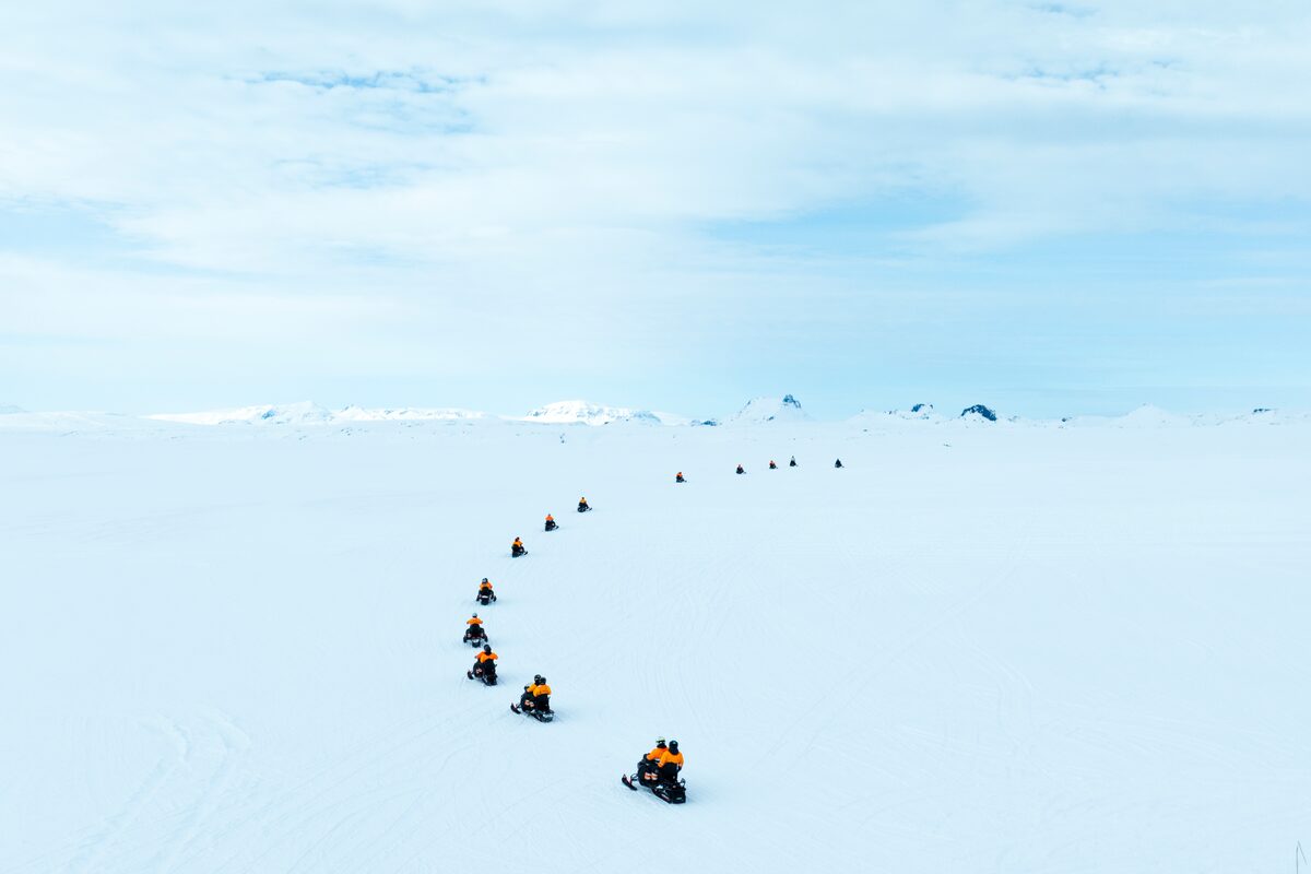 Snowmobiling Tour In Progress As Snowmobiles Drive In A Half Circle