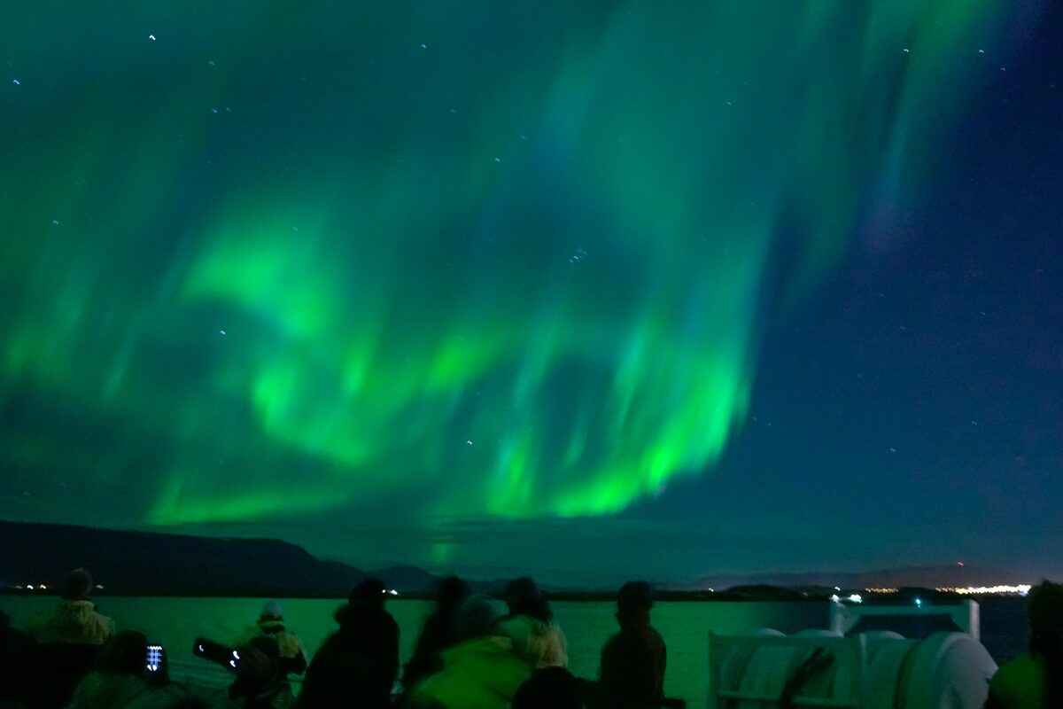 People On A Boat Looking At Northern Lights In Iceland