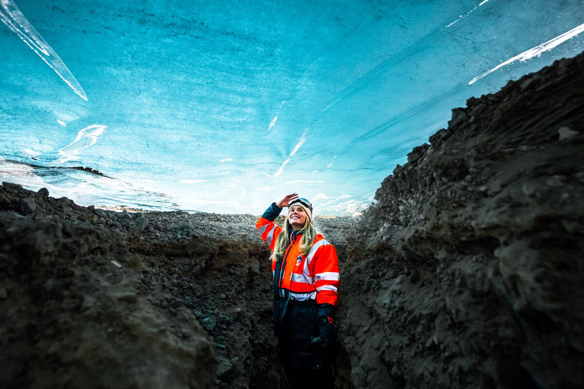 Woman Standing Under Ice In Ice Cave Smiling