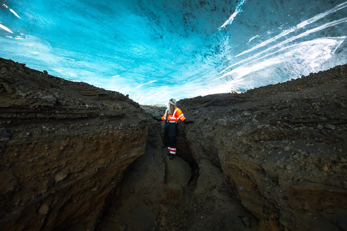 Woman Standing Under Ice Ceiling In An Ice Cave in iceland