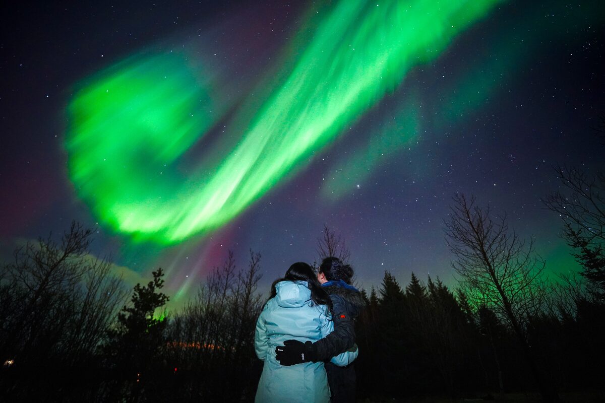 Couple Hugging And Looking At Northern Lights in iceland
