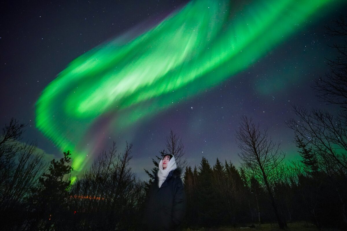 Woman Looking Up At The Sky With Northern Lights in iceland