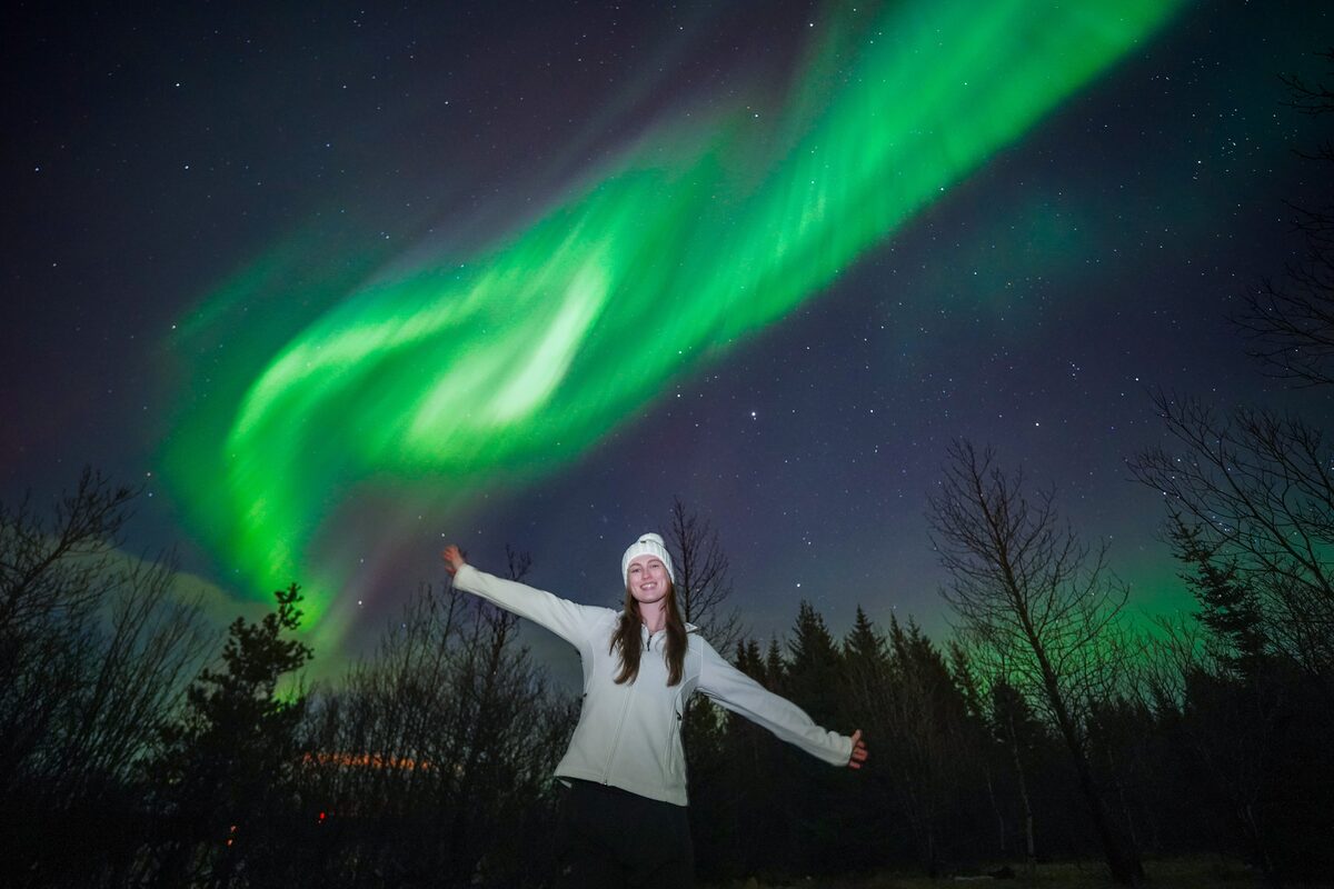Woman Spreading Arms Posing Under Northern Lights in iceland