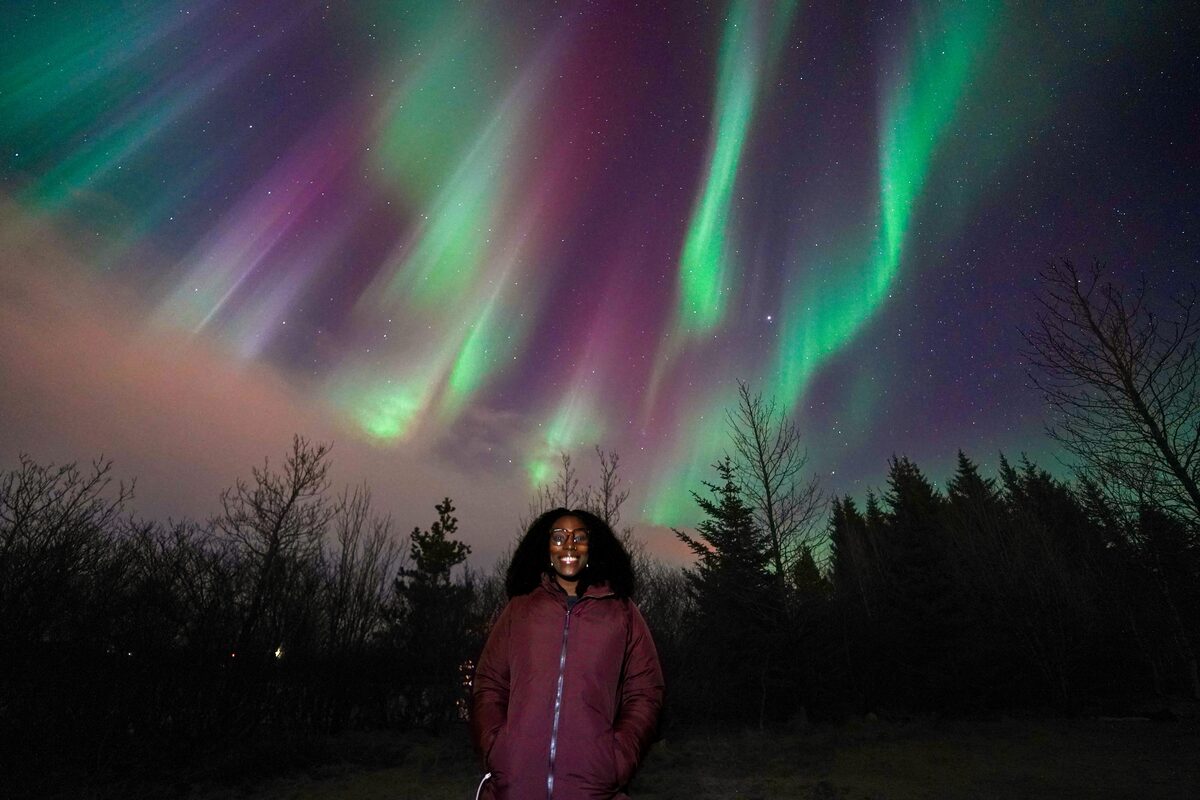 Woman Under Pink And Green Northern Lights in iceland