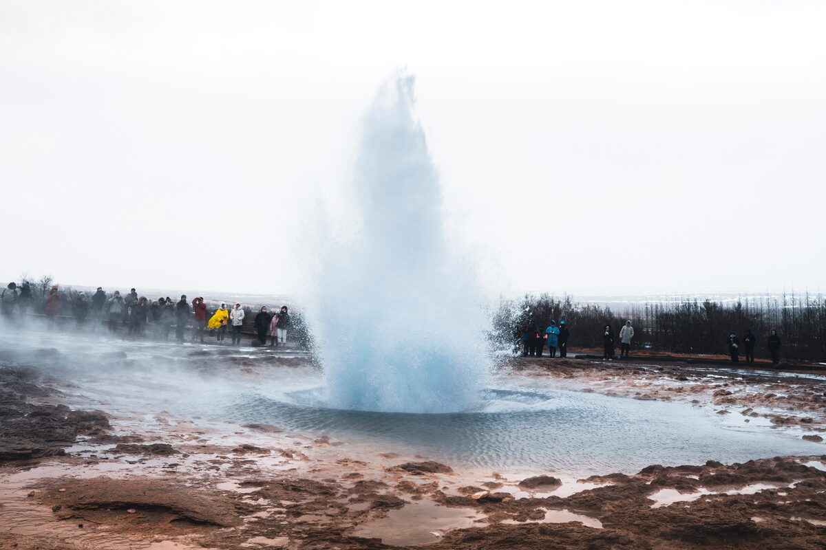 Tourists Looking At Erupting Geysir in iceland