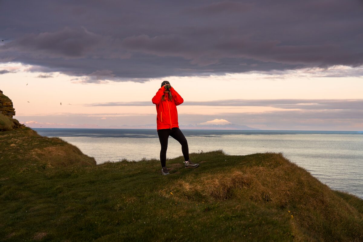 Woman Looking Through Binoculars In Westfjords in iceland