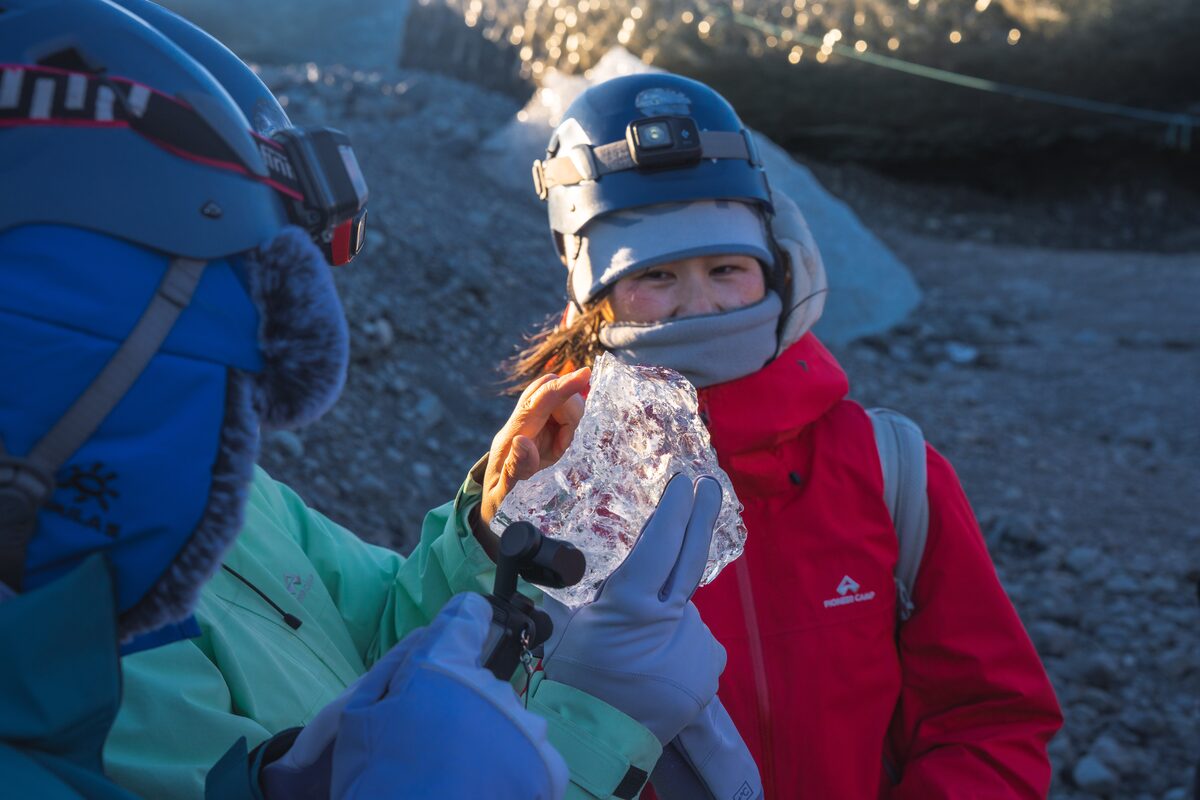 People Admiring A Piece Of Ice At Crystal Ice Cave in iceland