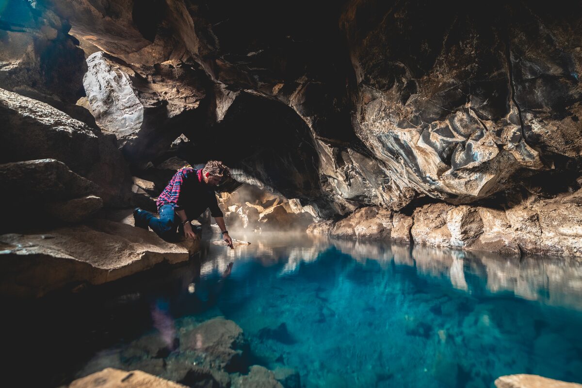 Man Trying To Touch Water At Grotagja Cave in iceland
