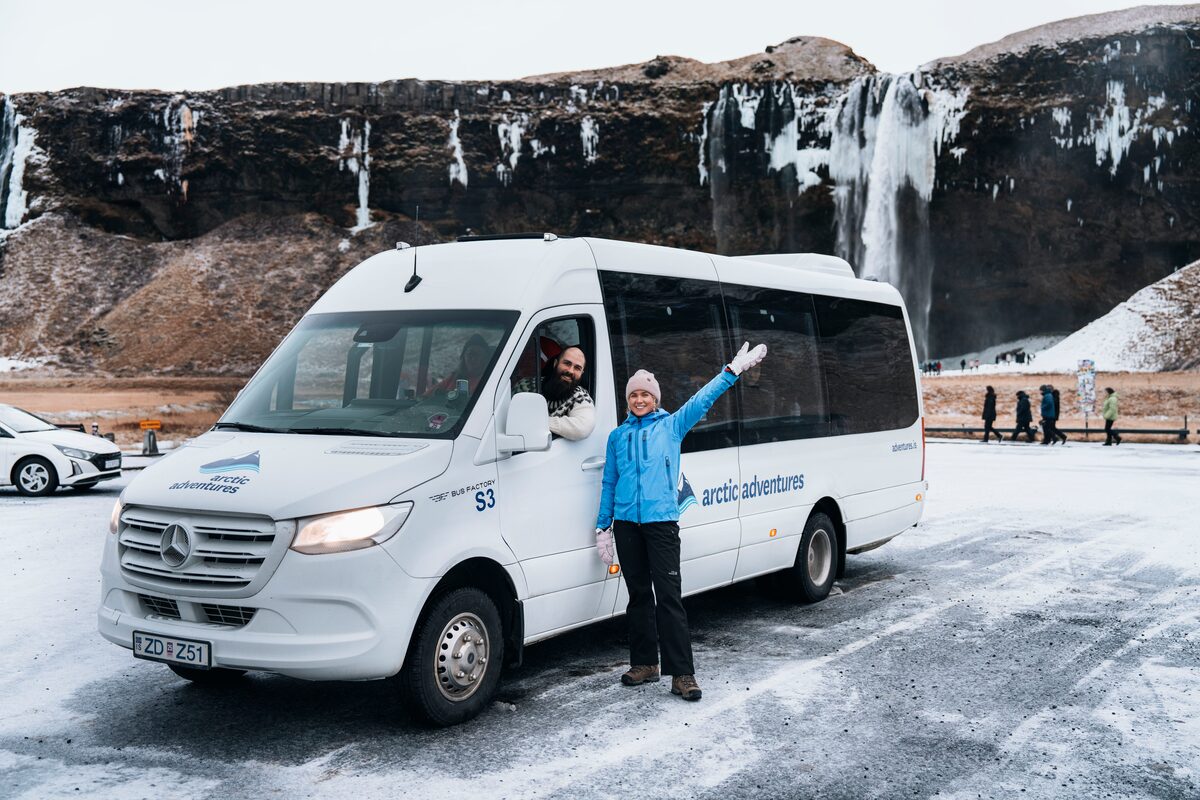 Woman Smilling And Waving Near A Tour Bus in iceland