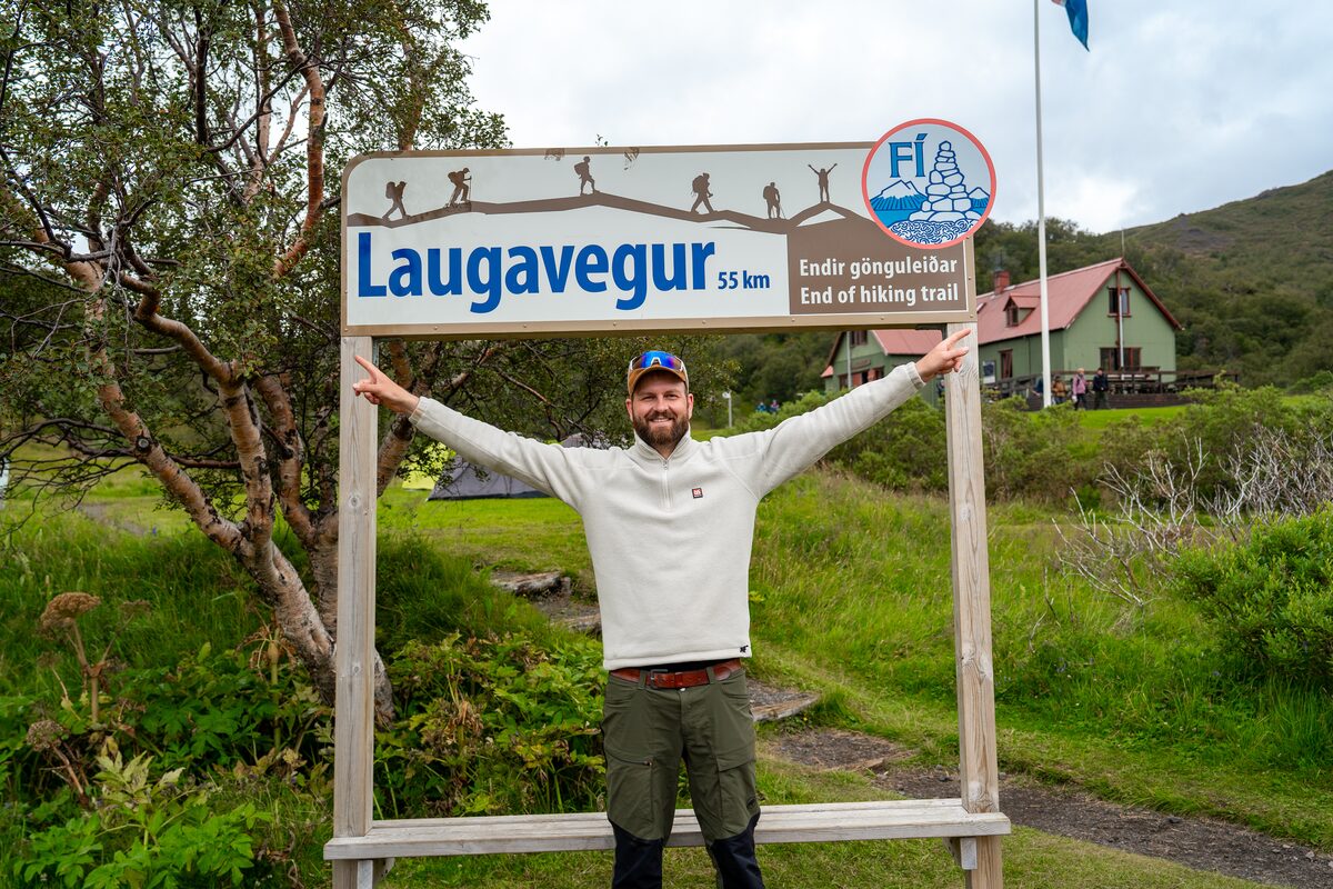 Man In A White Sweater With Laugavegur Sign Behind Him in Iceland