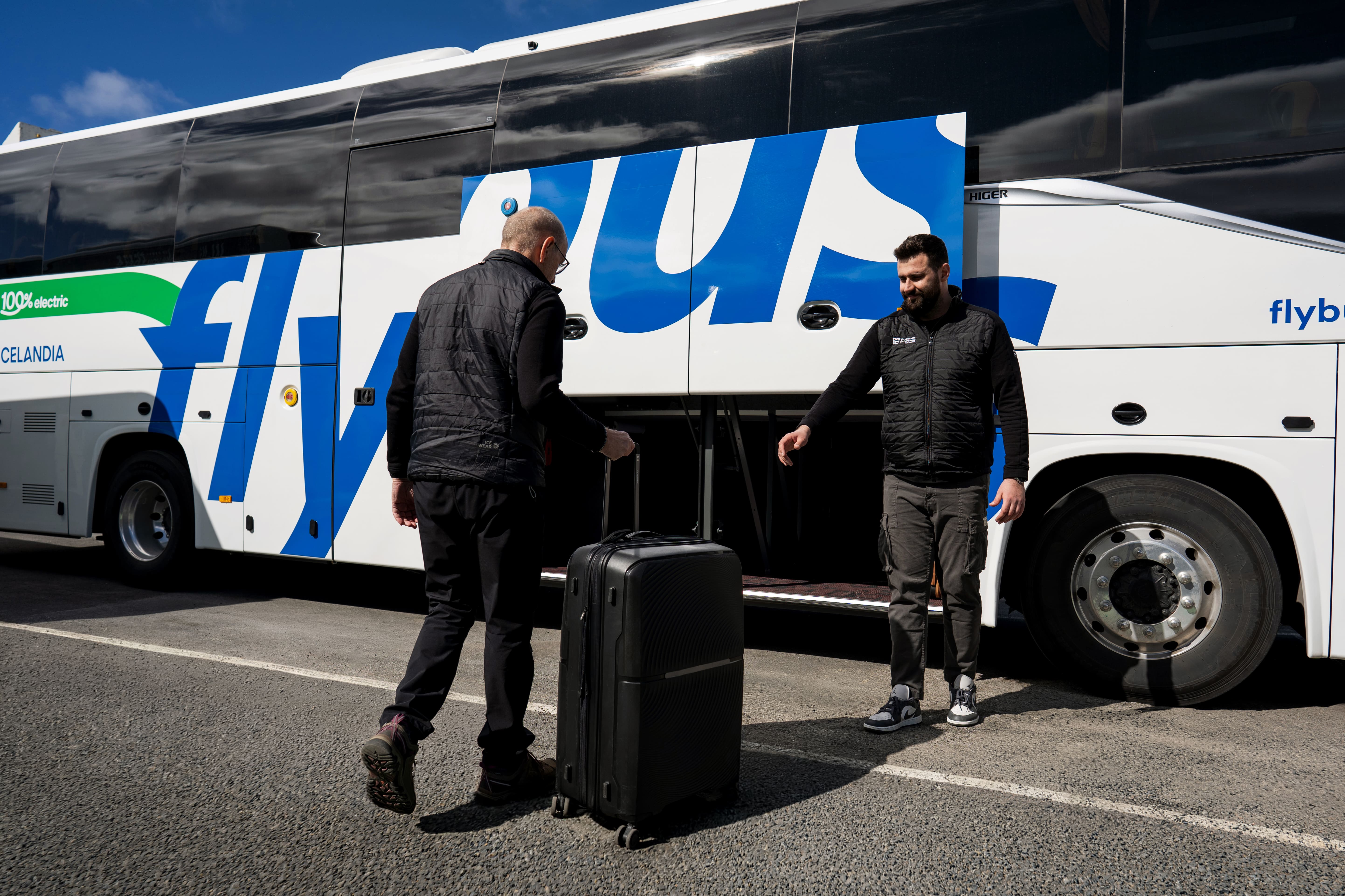 Person Giving His Luggage To A Bus Driver Near The Bus in Iceland