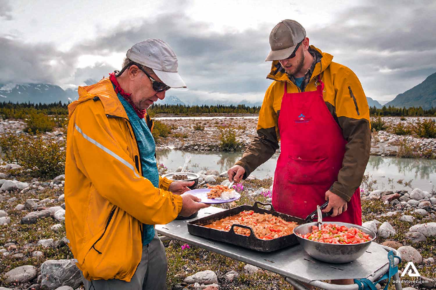 two men cooking food near Tatshenshini river