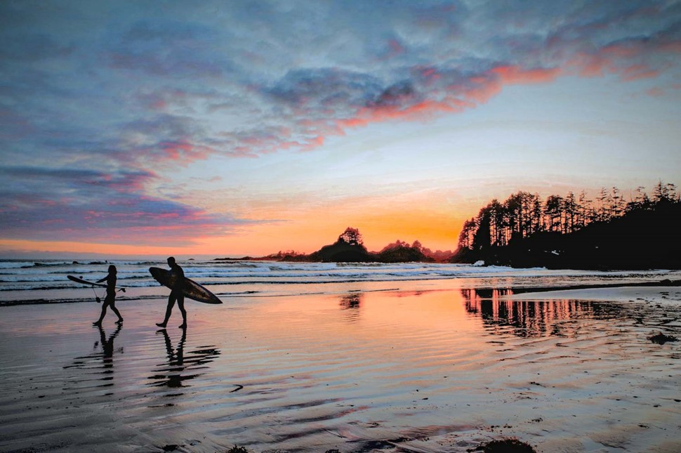 surfing at tofino beach in canada at sunset