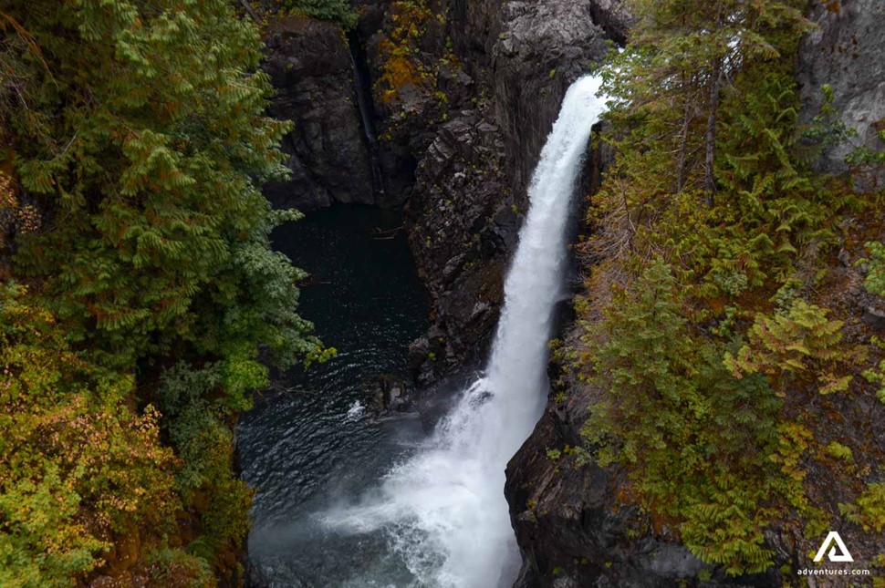 a waterfall in between a forest in canada vancouver island