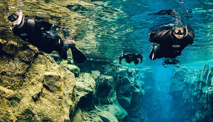 Four People Snorkeling Silfra Fissure In Iceland