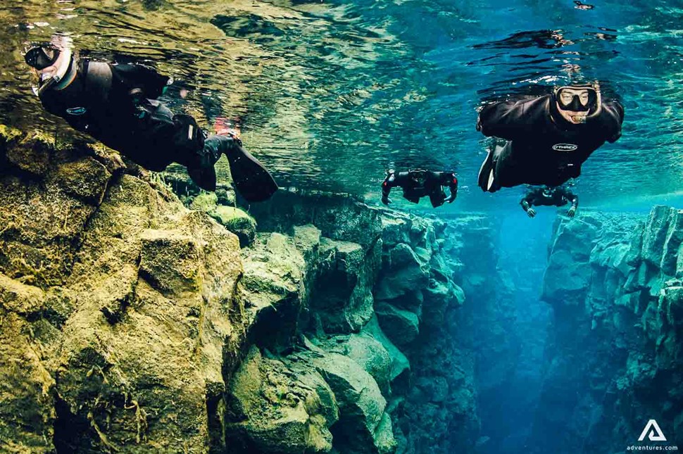 Four People Snorkeling Silfra Fissure In Iceland