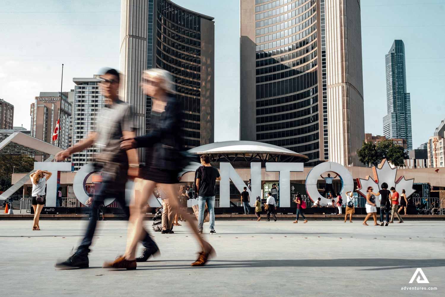 people walking past toronto city sign in canada