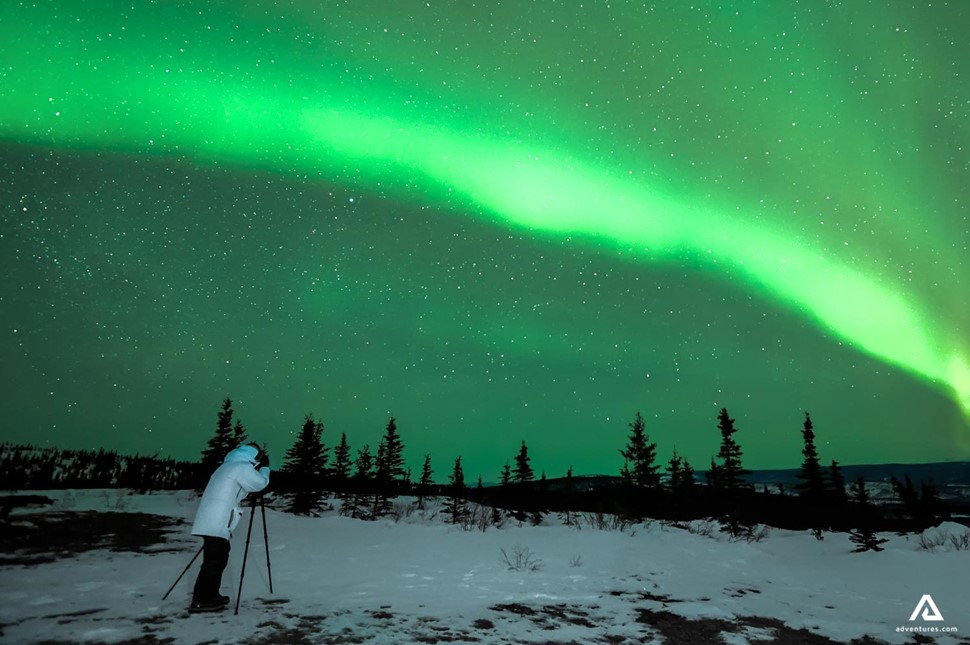tourist taking pictures of northern lights in winter