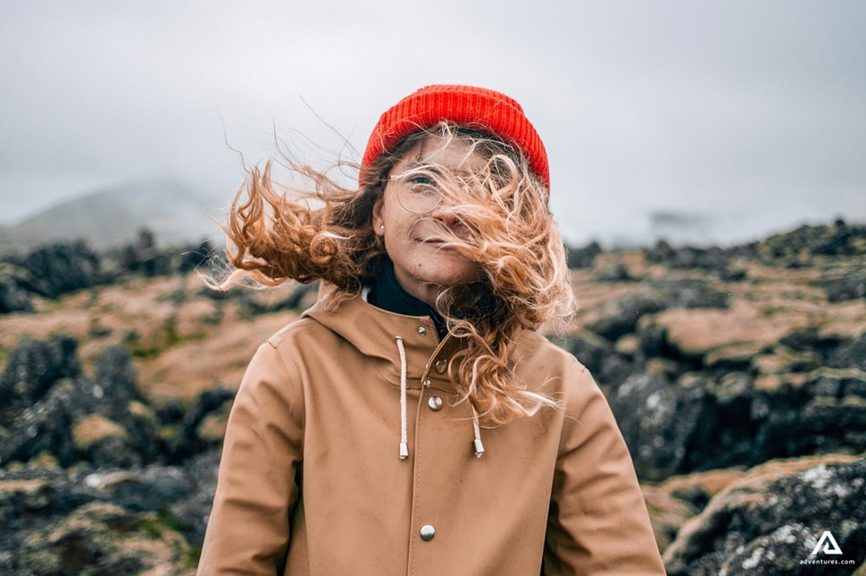 woman standing in a lava field on a windy day in iceland