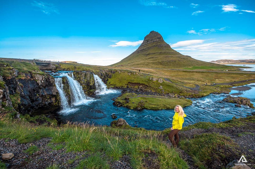 Woman in yellow jacket near Kirkjufell Fall in Iceland