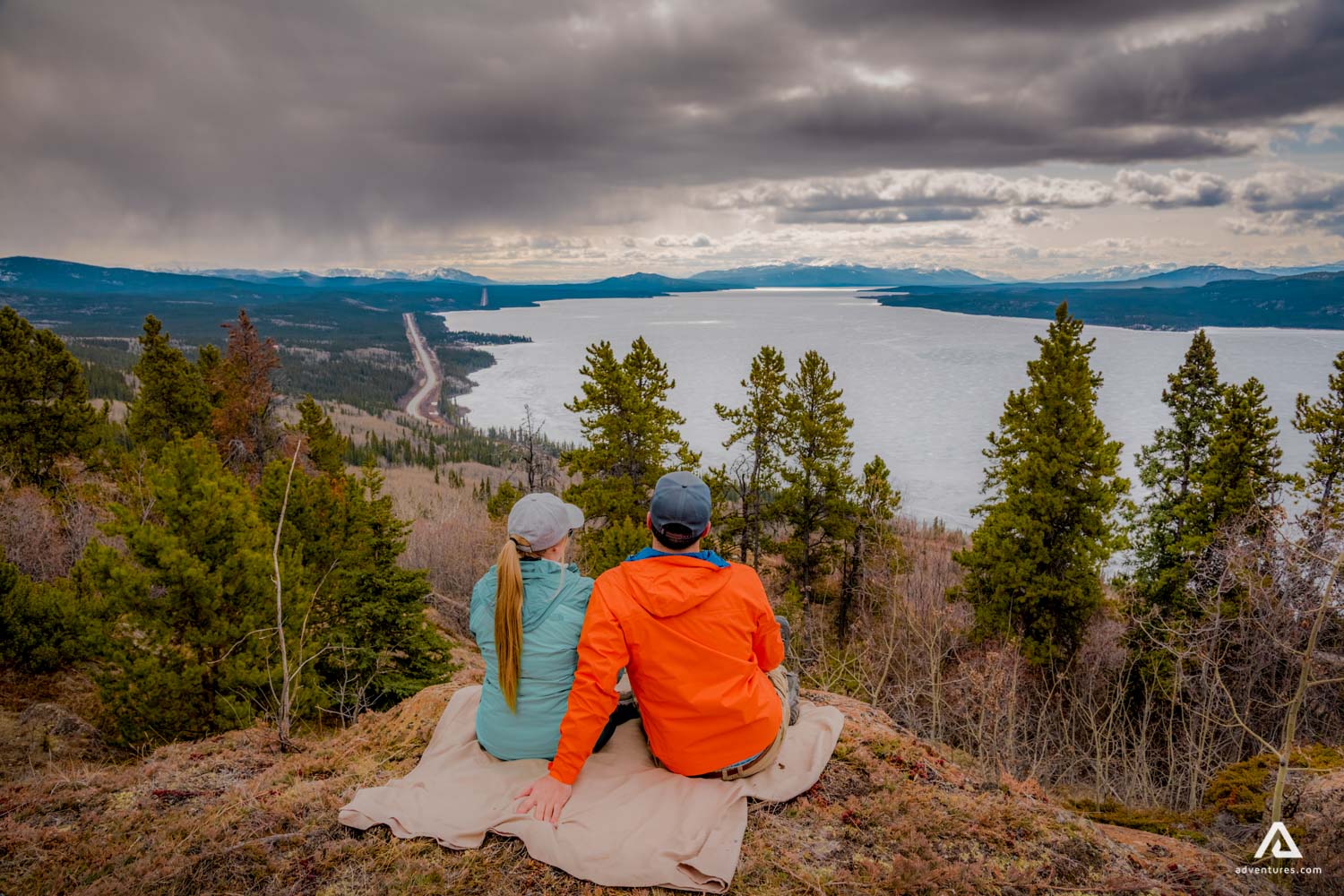 Couple sitting on the edge of a hill and enjoying Yukon Territory view