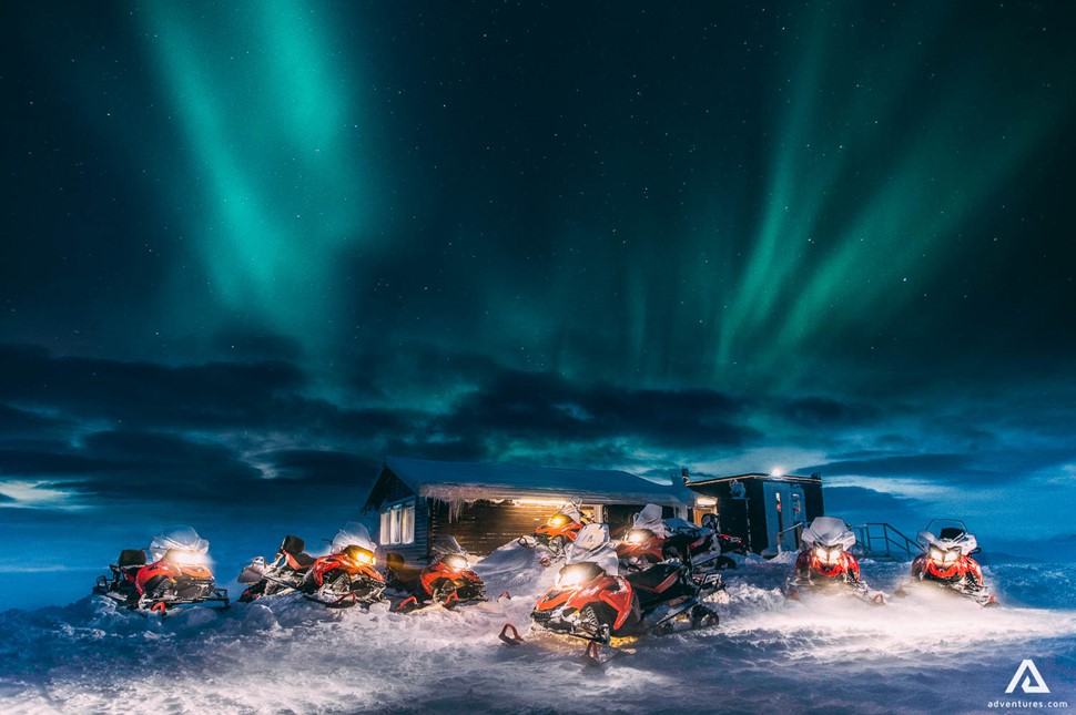 northern lights above snowmobiles on langjokull