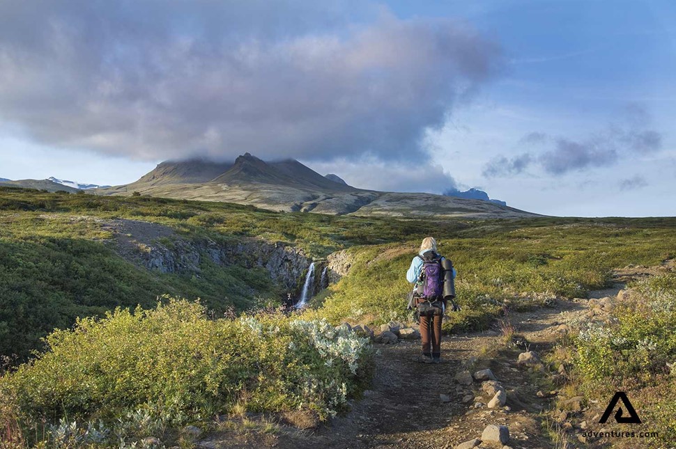 woman hiking towards svartifoss waterfall in skaftafell